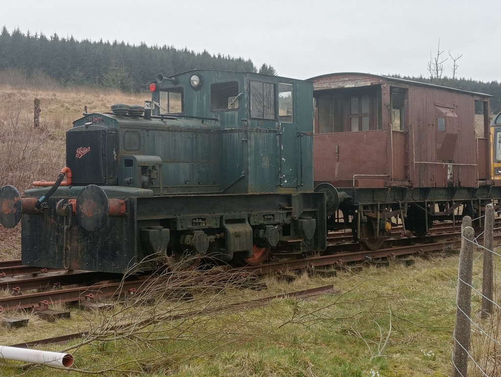 Dark green steam engine pulling a brown coal carriage.