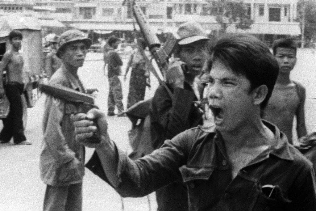 A Khmer Rouge soldier waves his pistol and orders store owners to abandon their shops in Phnom Penh, Cambodia, as communist forces take over the capital in April, 1975.