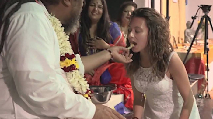 mooji feeds a woman wearing white lace; after she kissed his feet