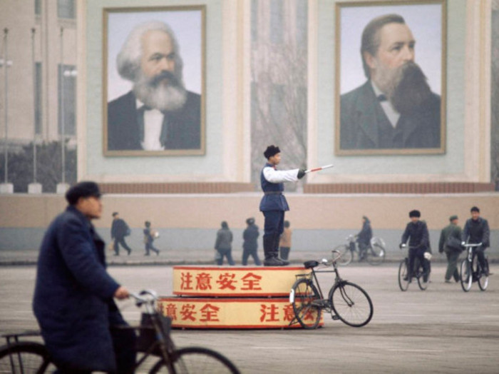 A traffic policeman in Tiananmen Square, standing before gigantic posters of Marx and Engels, Beijing, 1973.