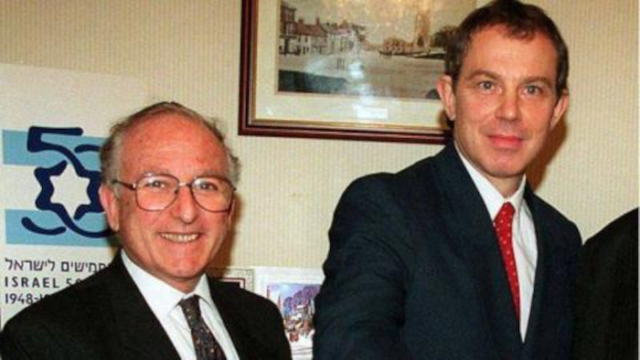 Greville Janner standing in front of a 50th Anniversary poster for the founding of Israel, probably in 1998, alongside Labour politician Tony Blair.