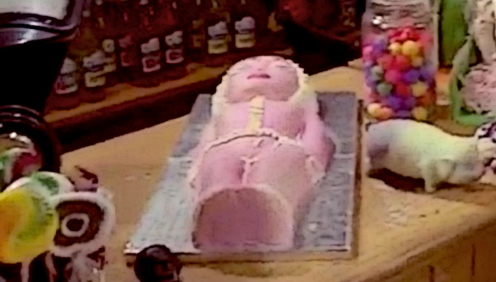 Screenshot of a blonde woman made into a cake, from the cult film Wicca Man